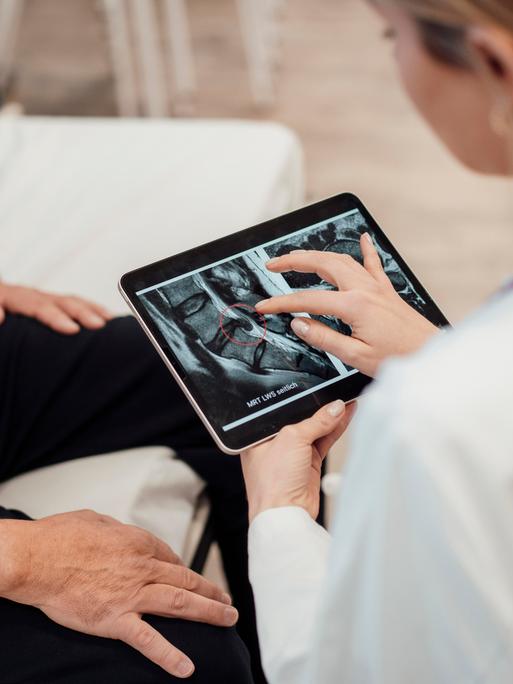 Doctor consulting with patient using tablet in medical office || Modellfreigabe vorhanden