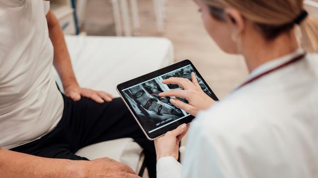 Doctor consulting with patient using tablet in medical office || Modellfreigabe vorhanden