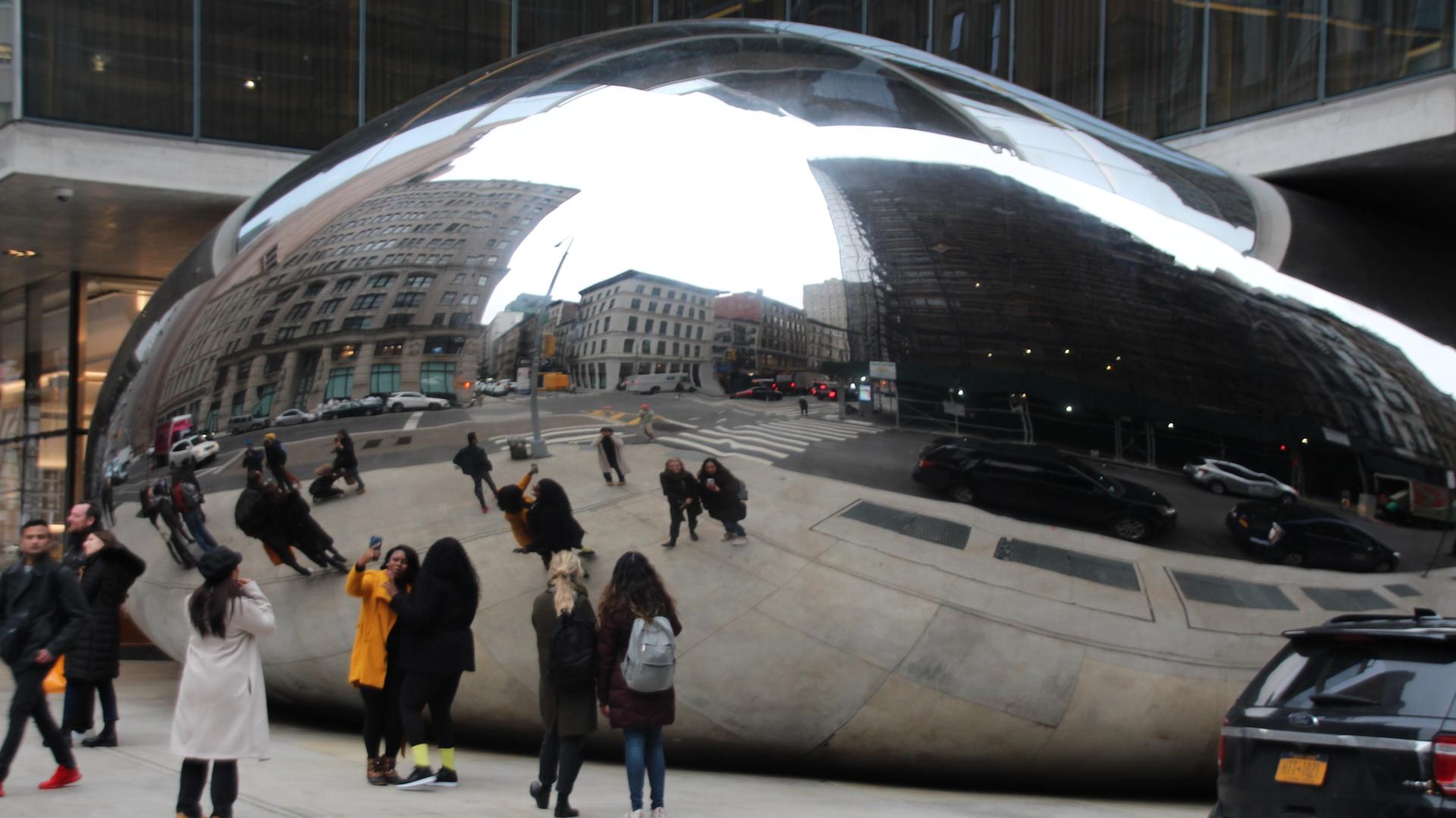 Menschen stehen vor einer großen metallisch-spiegelndenSkulptur des Künstler Anish Kapoor in New York