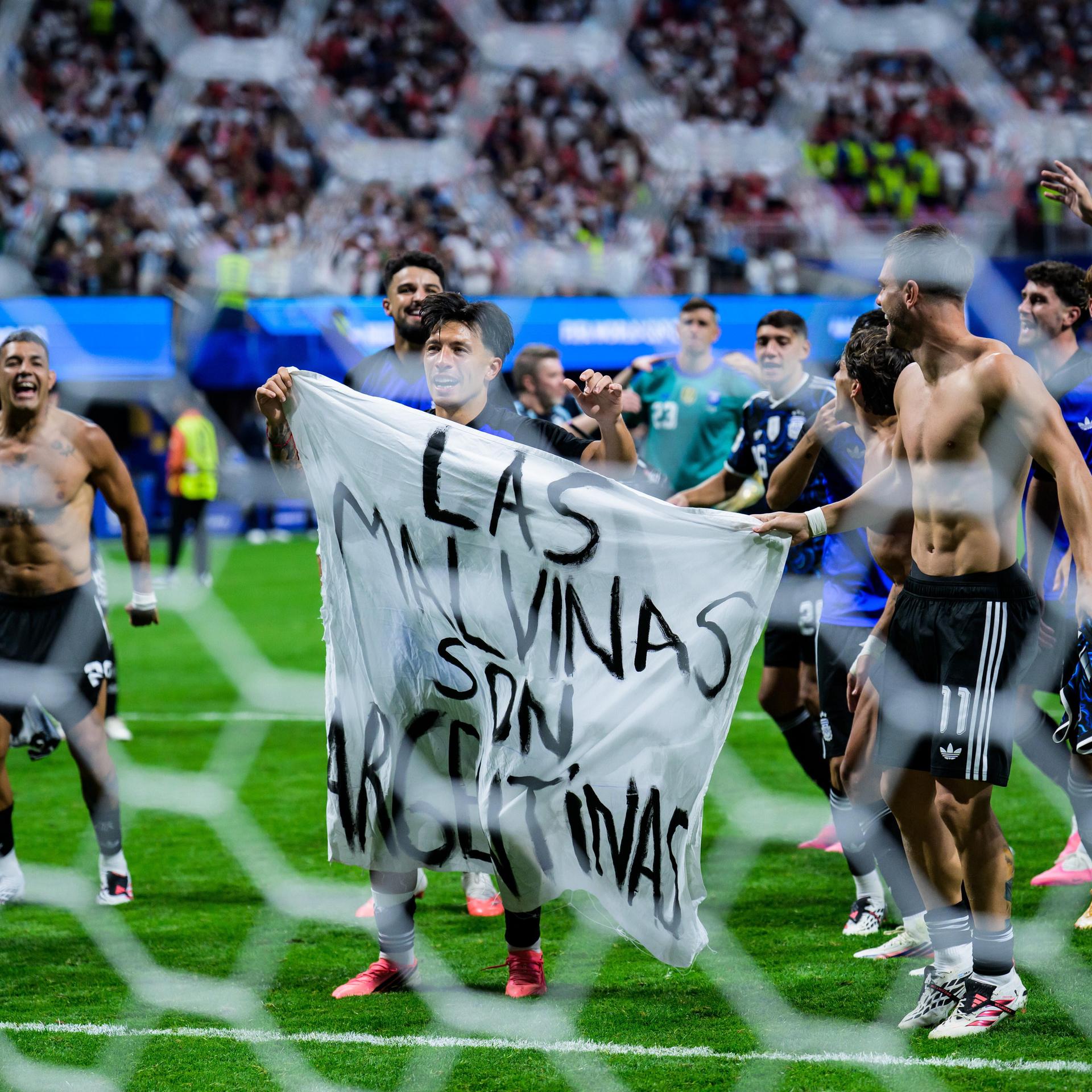 Die Argentinier Lisandro Martinez und Giovani Lo Celso halten nach dem Halbfinalspiel der FIFA-Fußball-Weltmeisterschaft 2026 zwischen England und Argentinien in Atlanta ein Banner mit der Aufschrift „Las Malvinas son argentinas“ in die Höhe.