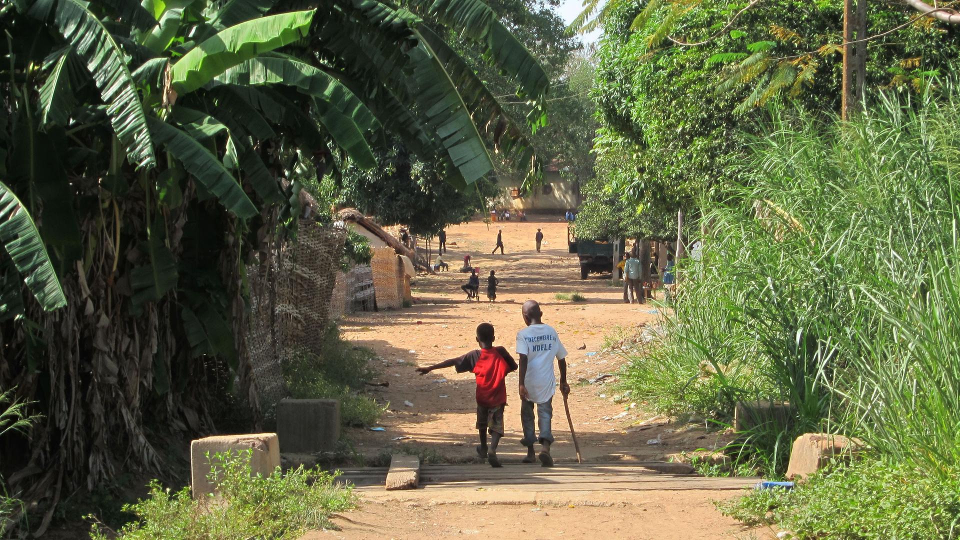 Zwei Kinder gehen eine Straße in der zentralafrikanischen Stadt Ndélé entlang. Sie sind von hinten und in größerer Entfernung zu sehen. 