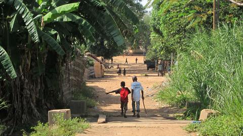 Zwei Kinder gehen eine Straße in der zentralafrikanischen Stadt Ndélé entlang. Sie sind von hinten und in größerer Entfernung zu sehen. 
