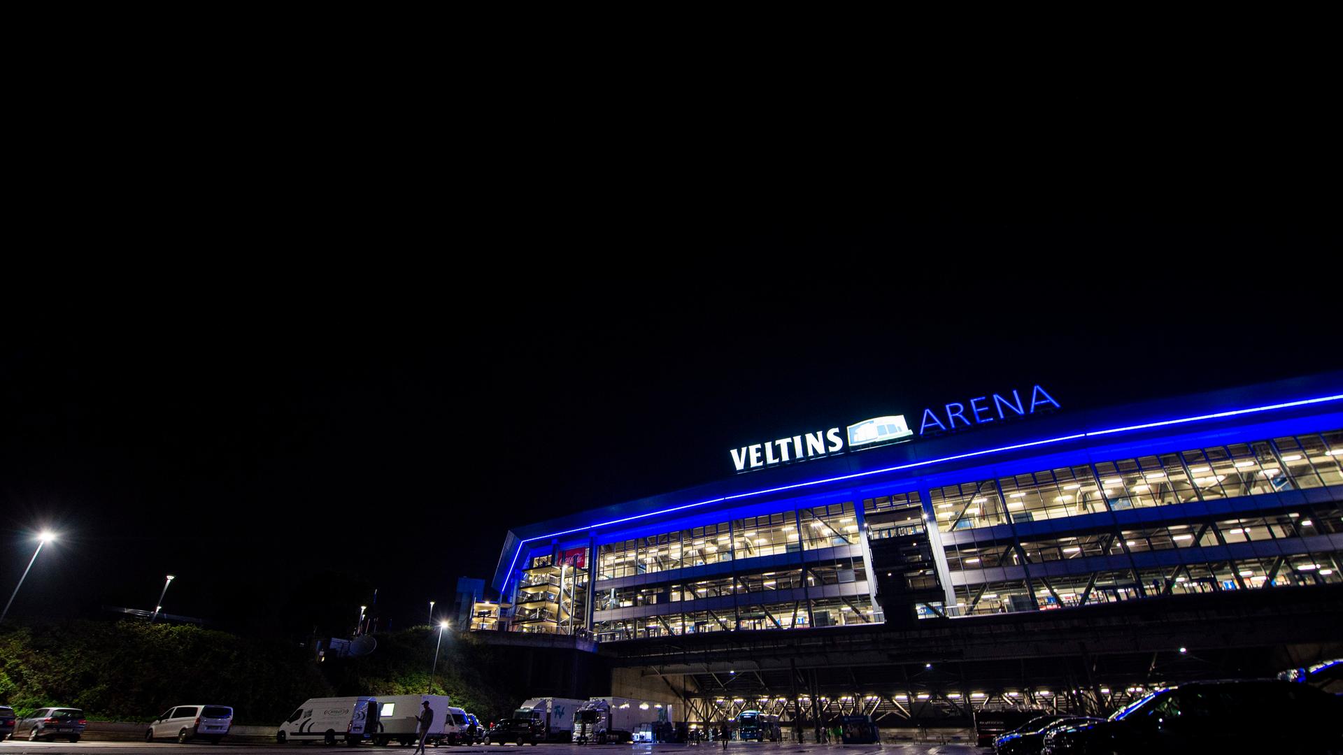 Die Schalker Veltins-Arena in der Nacht, in Fenstern ist Licht zu sehen. 