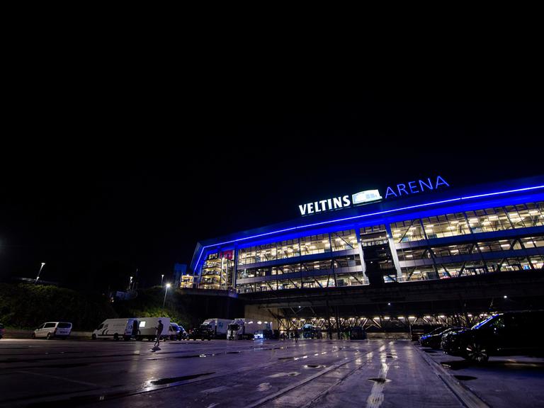 Die Schalker Veltins-Arena in der Nacht, in Fenstern ist Licht zu sehen. 