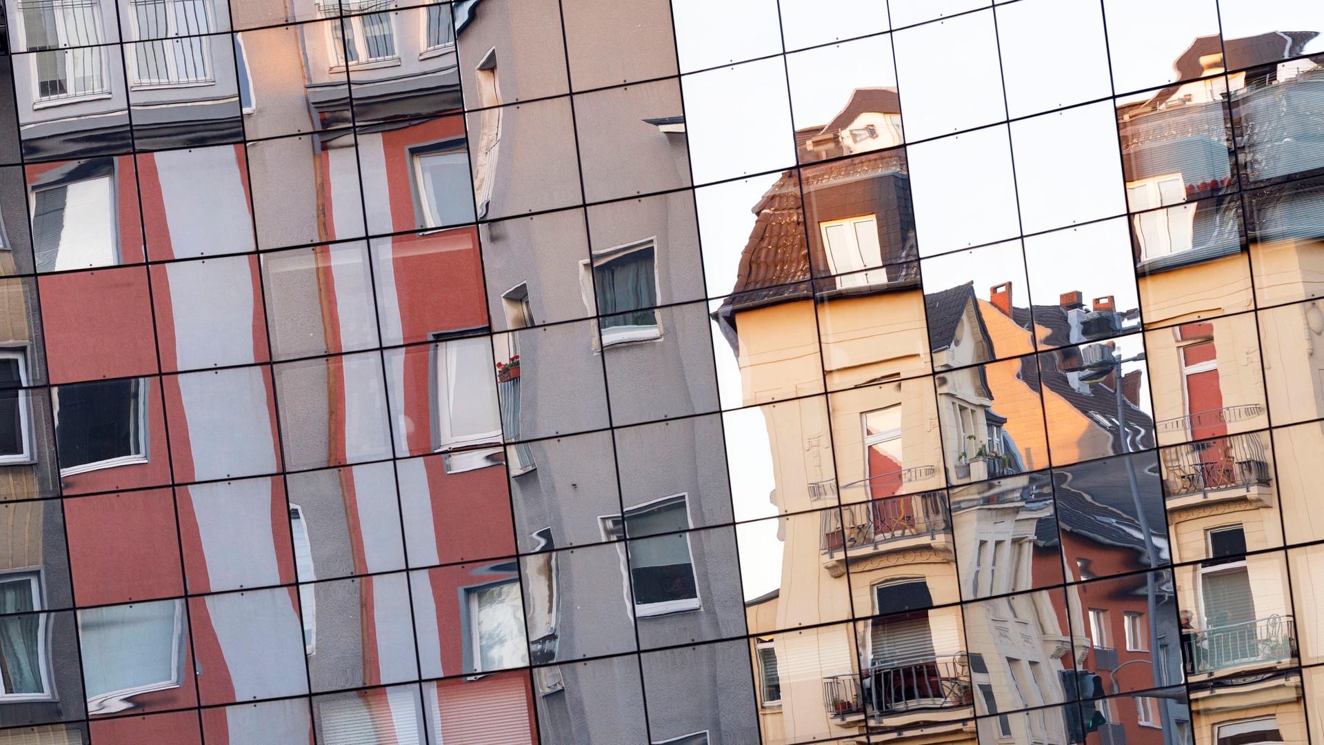 Unterschiedliche Wohnhäuser in der Kölner Innenstadt spiegeln sich in einer gegenüberliegenden Glasfassade