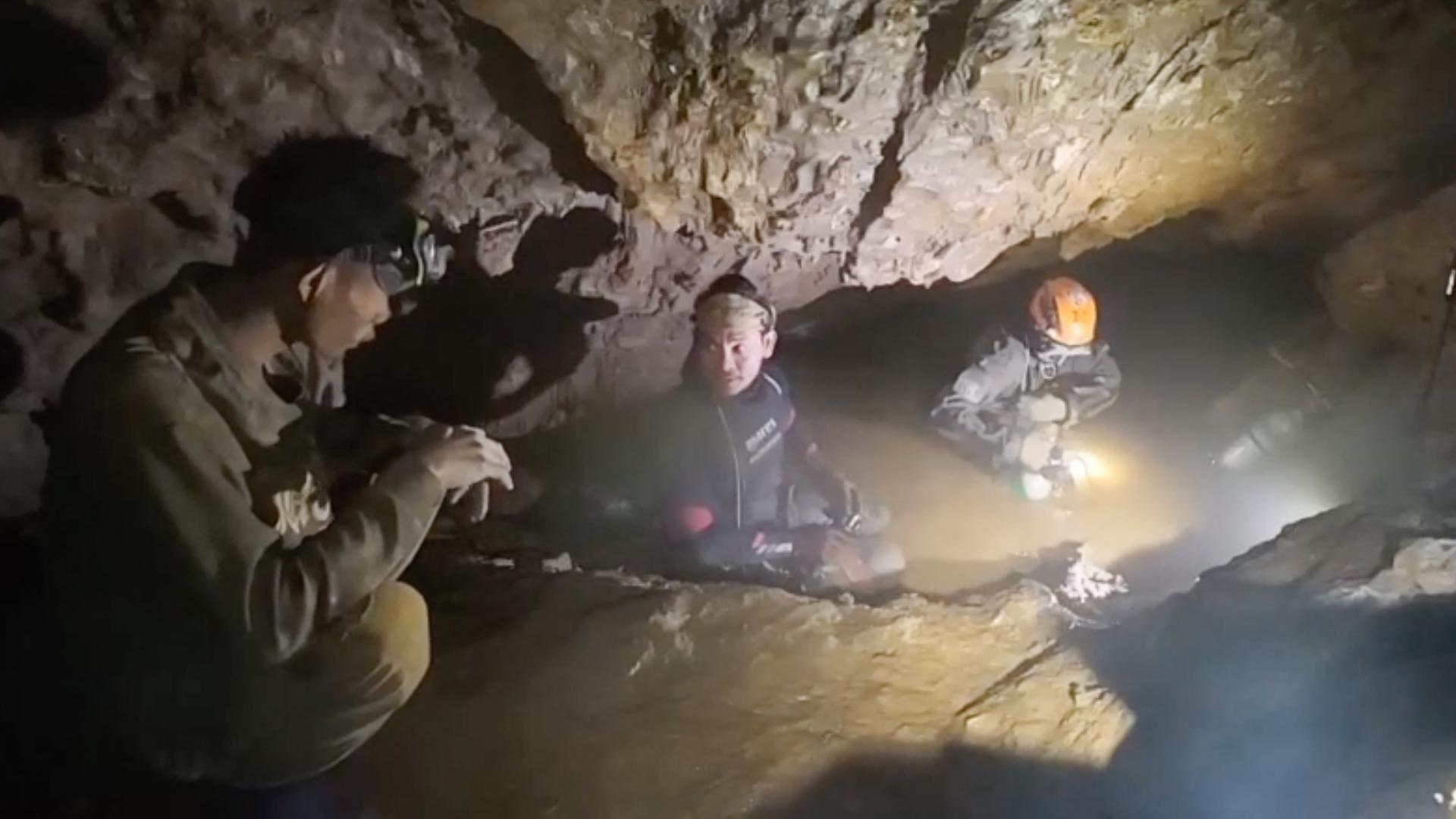 Es ist dunkel. Drei Männer vor dem Höhleneingang in Laos werden von einem Strahler beleuchtet. Es ist dunkel. Drei Männer vor dem Höhleneingang in Laos werden von einem Strahler beleuchtet.