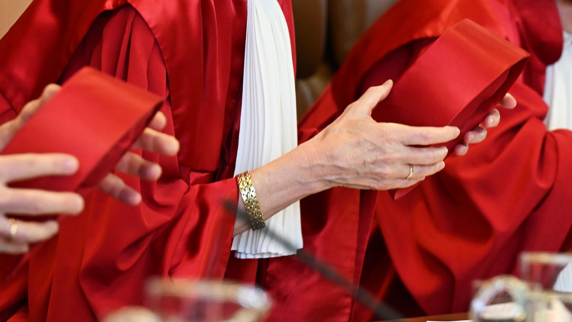Richterinnen und Richter des Zweiten Senats des Bundesverfassungsgerichts nehmen im Gerichtssaal ihre roten Kappen ab. Richterinnen und Richter des Zweiten Senats des Bundesverfassungsgerichts nehmen im Gerichtssaal ihre roten Kappen ab.