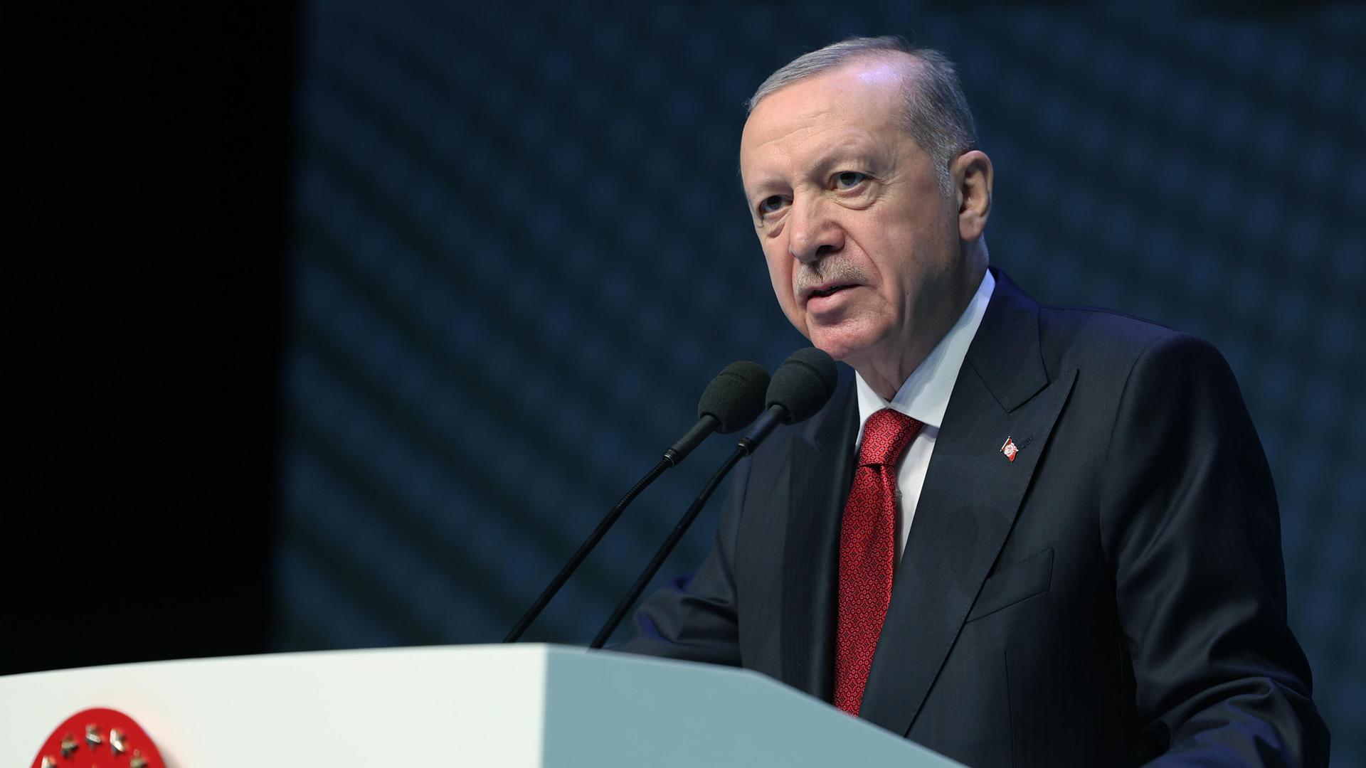 Recep Tayyip Erdogan steht an einem Rednerpult und spricht in ein Mikrofon.