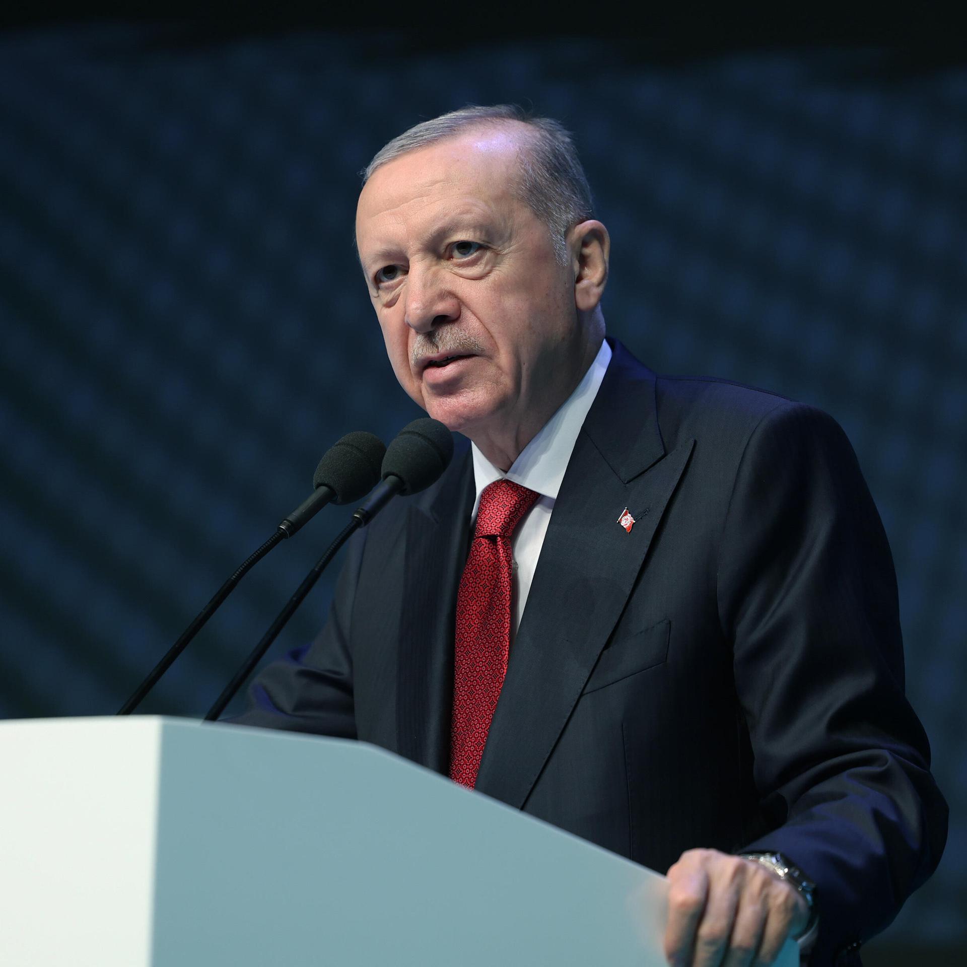 Recep Tayyip Erdogan steht an einem Rednerpult und spricht.