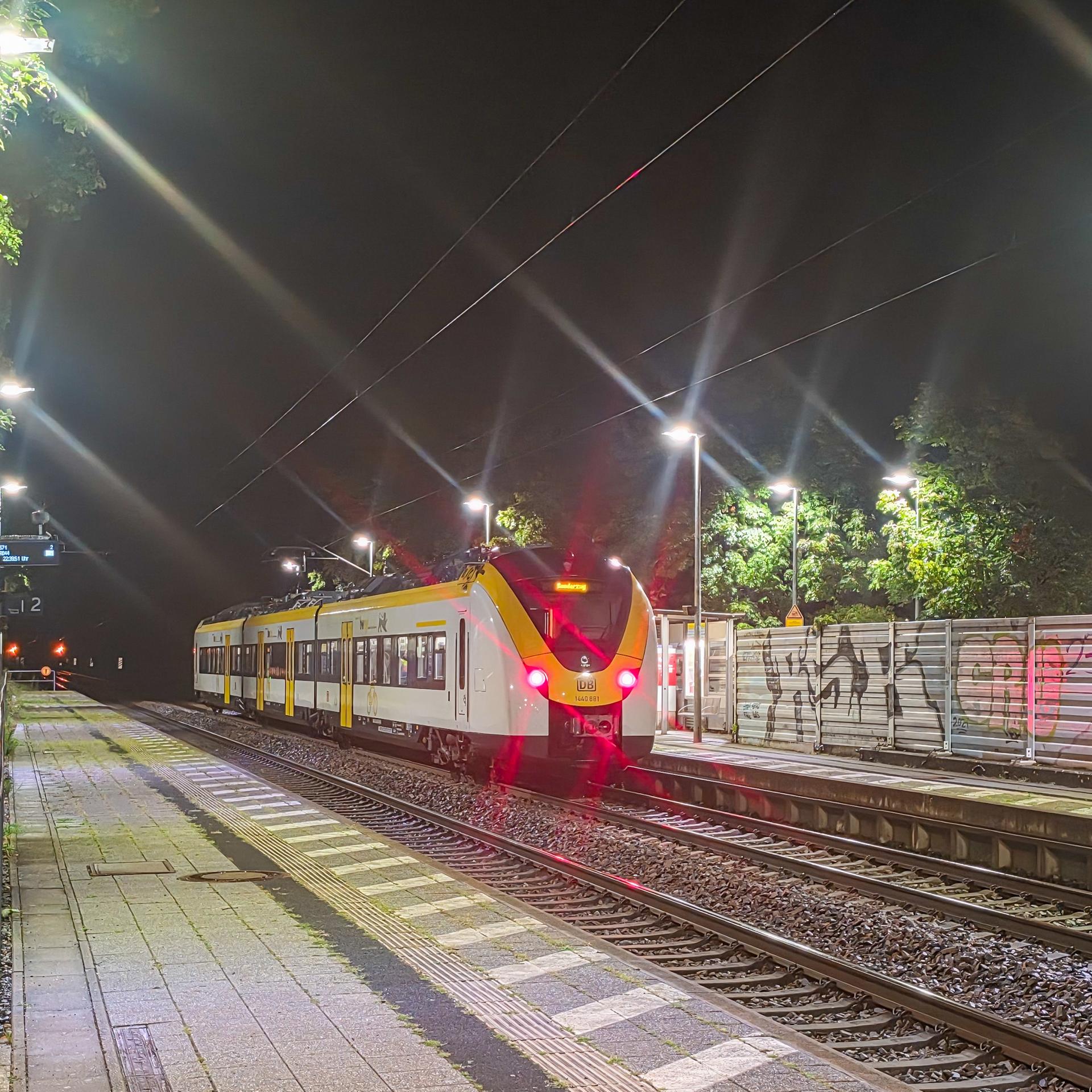 Ein Zug steht an einem Bahnhof auf den Gleisen. Es ist Nacht.