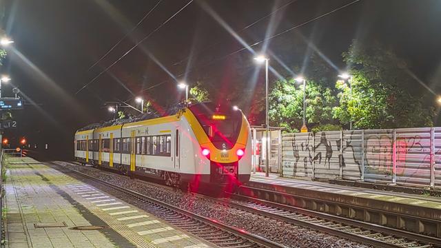 Ein Zug steht an einem Bahnhof auf den Gleisen. Es ist Nacht.