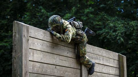 Ein Rekrut der Bundeswehr überwindet auf einem Hindernisparcours Holzlatten. 