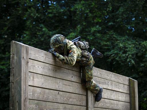Ein Rekrut der Bundeswehr überwindet auf einem Hindernisparcours Holzlatten. 