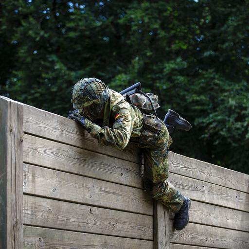Ein Rekrut der Bundeswehr überwindet auf einem Hindernisparcours Holzlatten. 