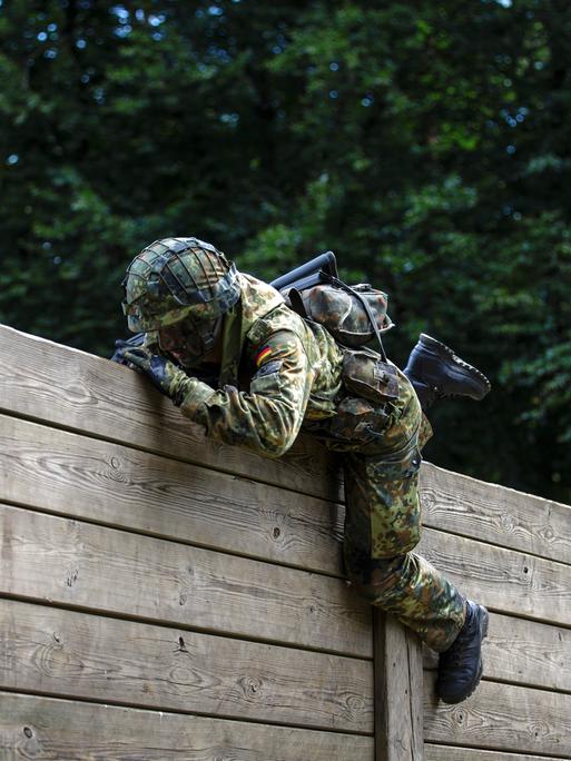 Ein Rekrut der Bundeswehr überwindet auf einem Hindernisparcours Holzlatten. 