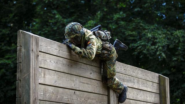 Ein Rekrut der Bundeswehr überwindet auf einem Hindernisparcours Holzlatten. 