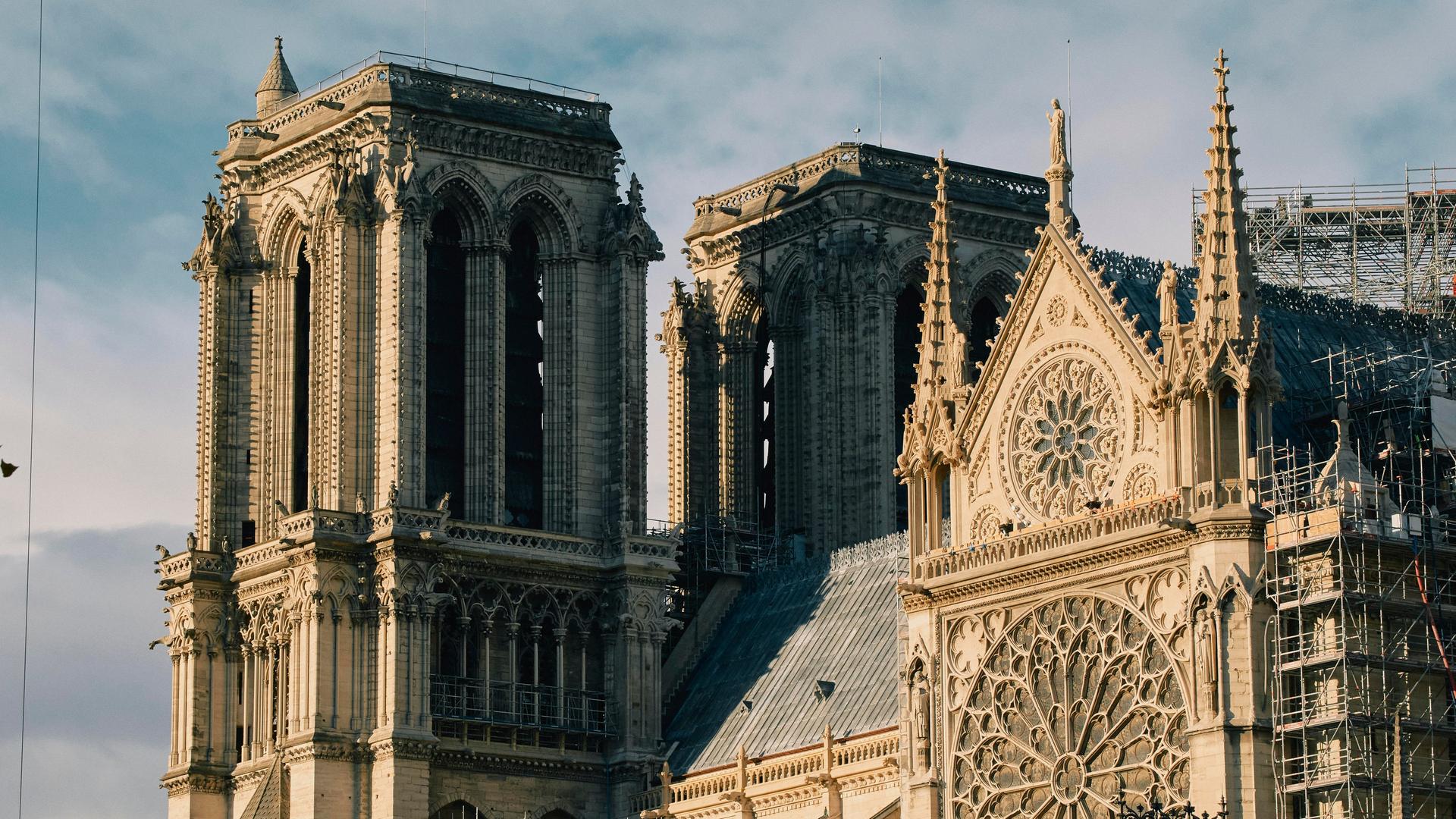 Außenansicht von Notre-Dame: Die Kathedrale hat beeindruckende Fenster, viele Verzierungen an der Fassade und Türme.