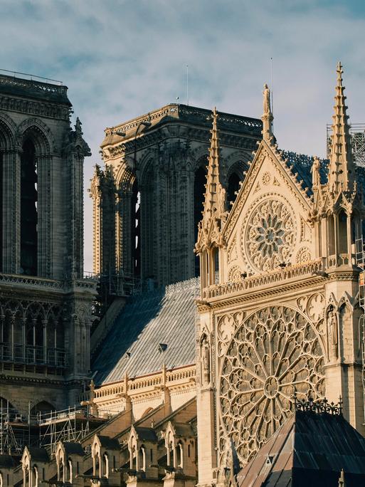 Außenansicht von Notre-Dame: Die Kathedrale hat beeindruckende Fenster, viele Verzierungen an der Fassade und Türme.