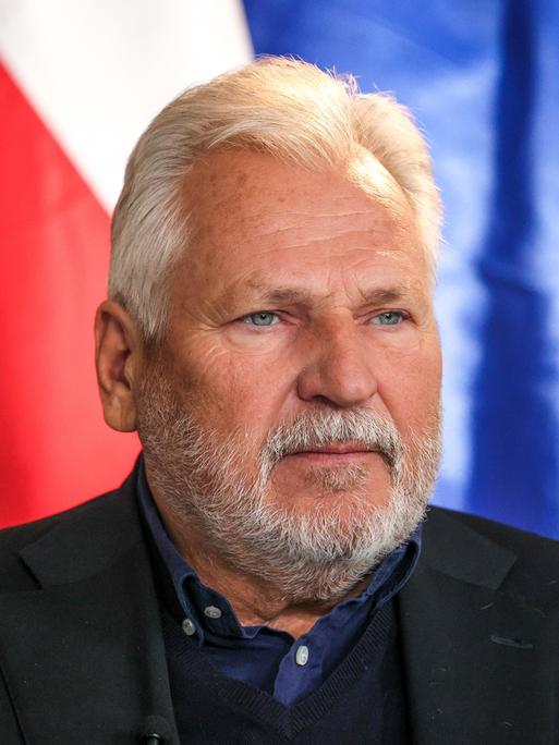 Der frühere polnische Präsident Aleksander Kwasniewski mit weißem Bart vor der polnischen und der EU-Fahne. 