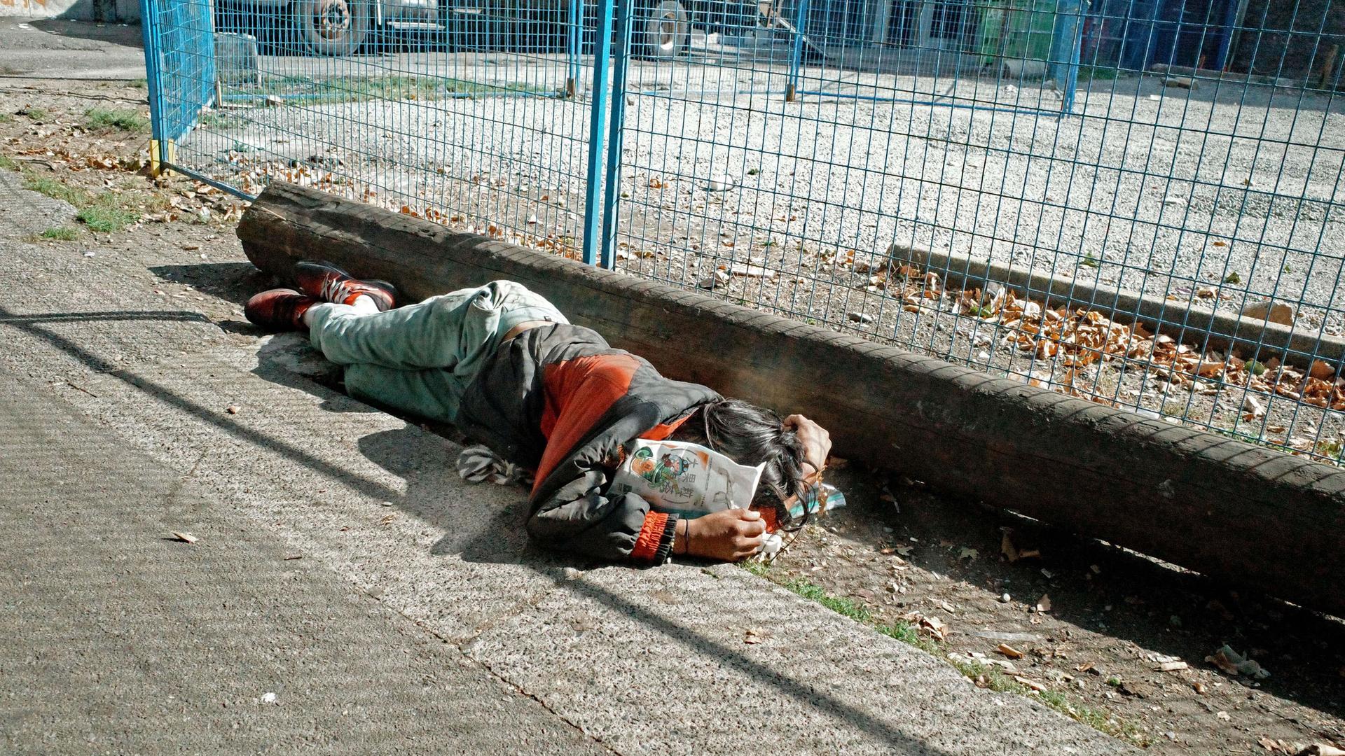 Eine Person schläft am Straßenrand. Eine Person schläft am Straßenrand.