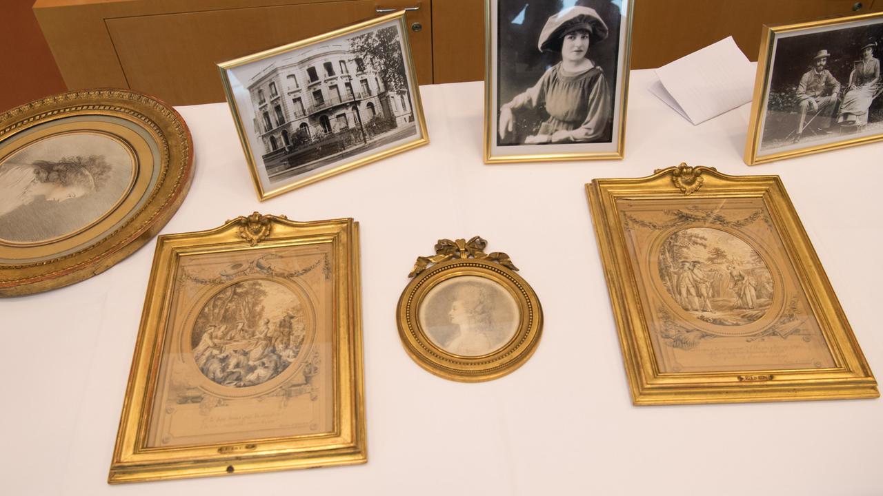 Blick auf vier als NS-Raubkunst identifizierte Zeichnungen, die an die Erben der ursprünglichen Eigentümerin zurückgegeben wurden, und daneben Fotos.