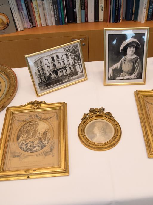 Blick auf vier als NS-Raubkunst identifizierte Zeichnungen, die an die Erben der ursprünglichen Eigentümerin zurückgegeben wurden, und daneben Foto.