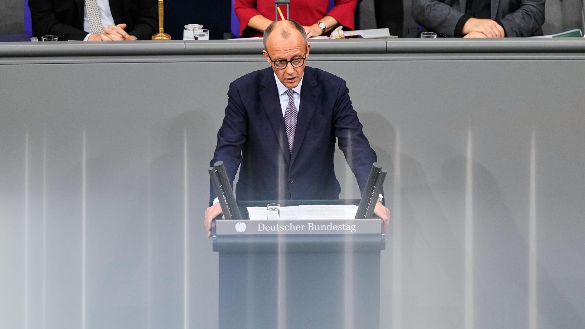 Bundeskanzler Merz steht im Bundestag hinter einem Rednerpult. Bundeskanzler Merz steht im Bundestag hinter einem Rednerpult.