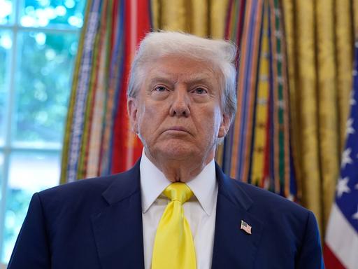 US-Präsident Donald Trump steht vor den Fahnen im Oval Office des Weißen Hauses in Washington und schaut mit ernstem Gesichtsausdruck