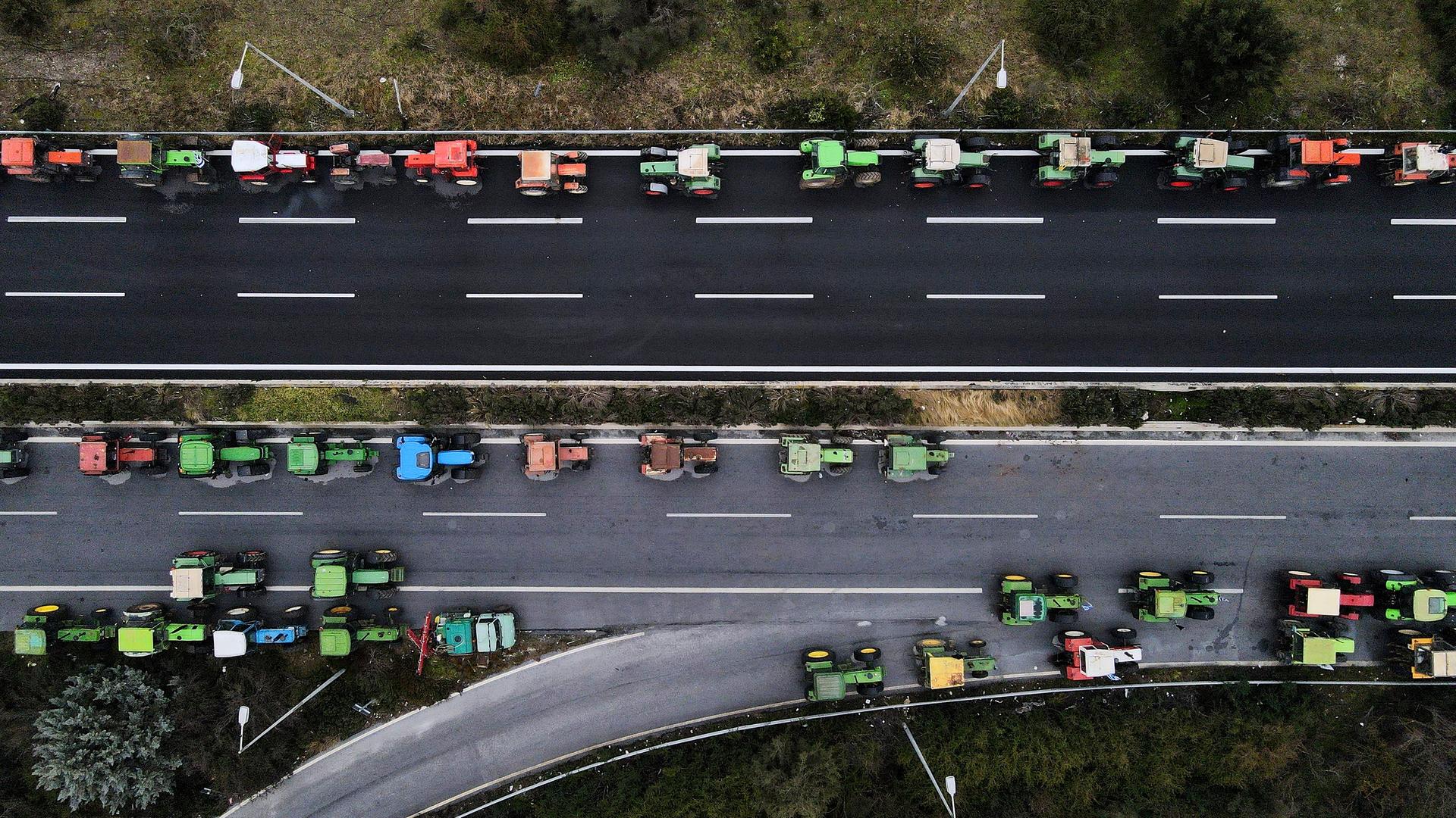 Traktoren sind während eines Protestes von Landwirten entlang einer Autobahn geparkt. Das Foto ist aus der Vogelperspektive aufgenommen.