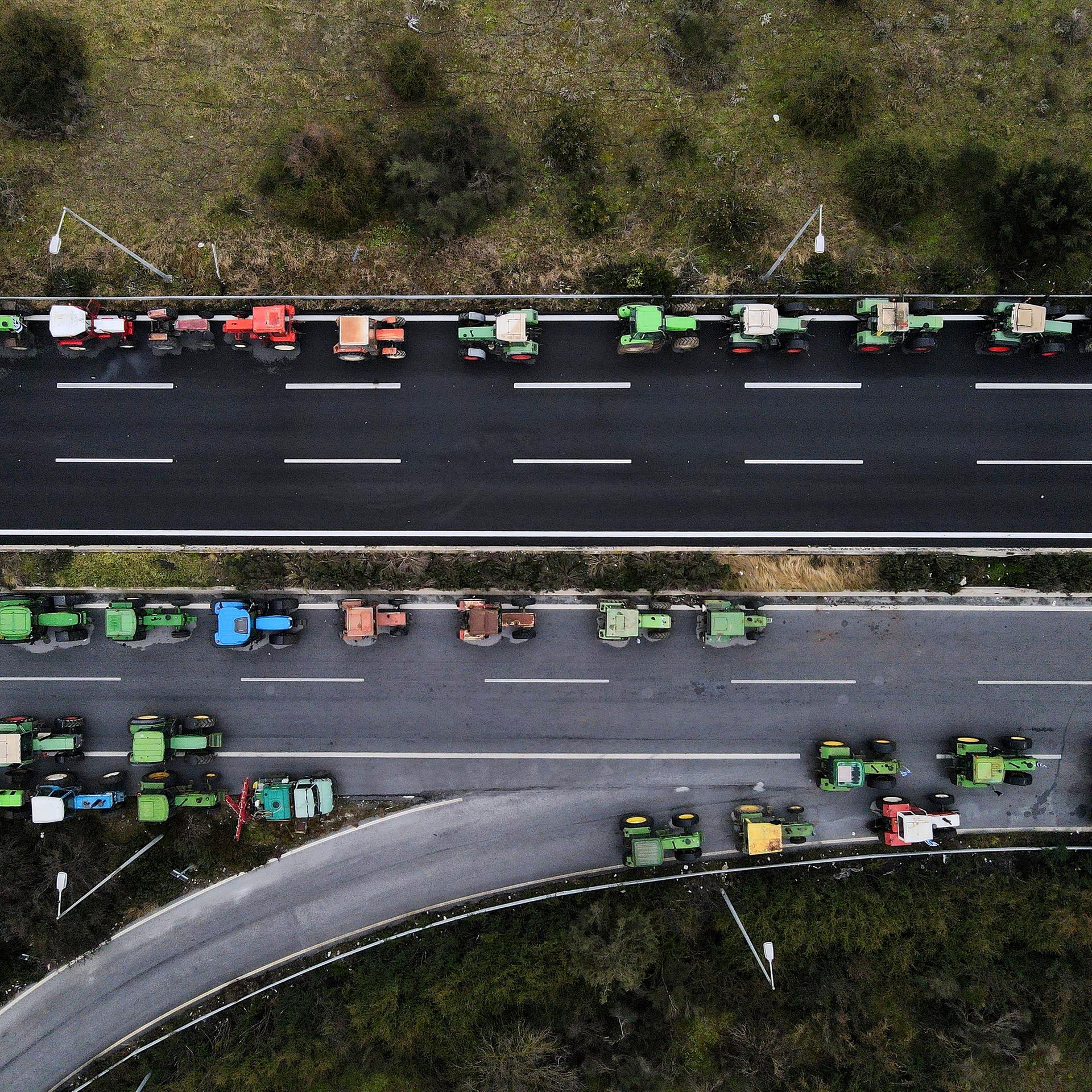 Traktoren sind während eines Protestes von Landwirten entlang einer Autobahn geparkt. Das Foto ist aus der Vogelperspektive aufgenommen.