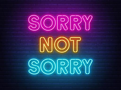 "Sorry not Sorry" Neonbuchstaben vor einer dunklen Ziegelmauer