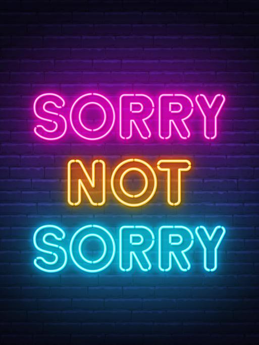 "Sorry not Sorry" Neonbuchstaben vor einer dunklen Ziegelmauer