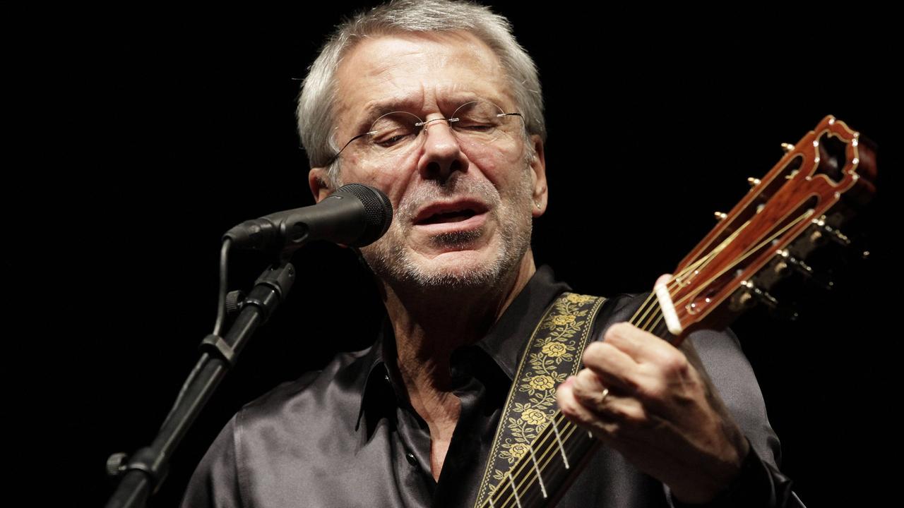 Reinhard Mey steht am Mikro und singt mit der Gitarre in der Hand. 