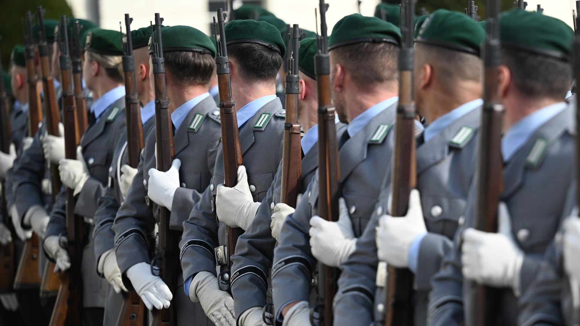 Soldatinnen und Soldaten der Bundeswehr stehen für eine Zeremonie mit Gewehren in einer Reihe.