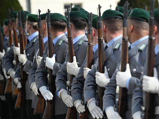 Soldatinnen und Soldaten der Bundeswehr stehen für eine Zeremonie mit Gewehren in einer Reihe.