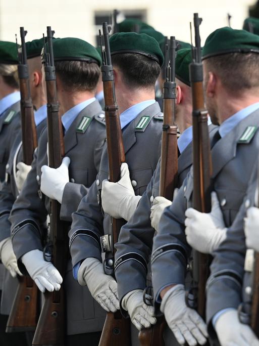 Soldatinnen und Soldaten der Bundeswehr stehen für eine Zeremonie mit Gewehren in einer Reihe.