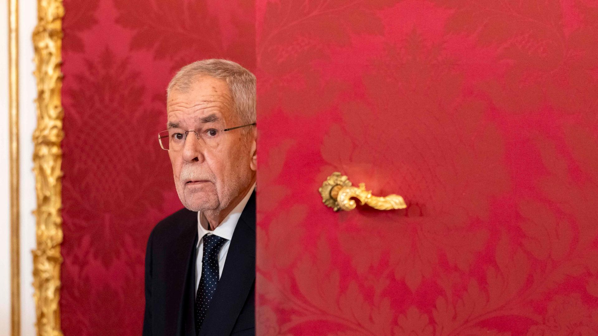 Der österreichische Bundespräsident Alexander Van der Bellen ist in der Präsidentschaftskanzlei in Wien und kommt hinter einer roten Tür mit goldenem Türgriff hervor. 