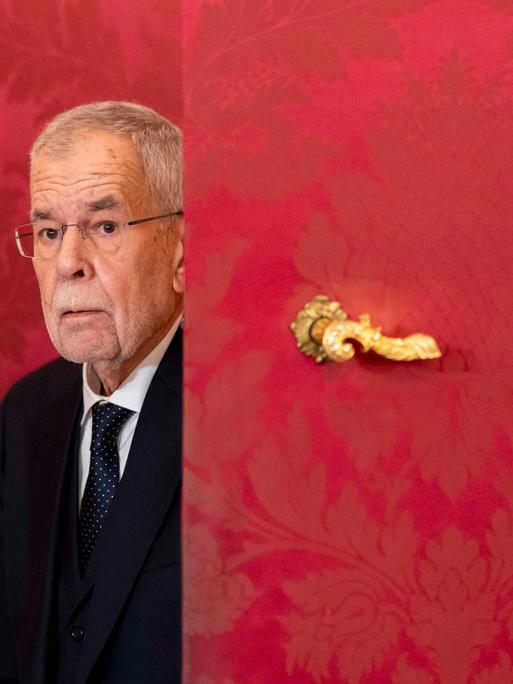 Der österreichische Bundespräsident Alexander Van der Bellen ist in der Präsidentschaftskanzlei in Wien und kommt hinter einer roten Tür mit goldenem Türgriff hervor. 