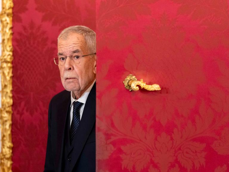 Der österreichische Bundespräsident Alexander Van der Bellen ist in der Präsidentschaftskanzlei in Wien und kommt hinter einer roten Tür mit goldenem Türgriff hervor. 