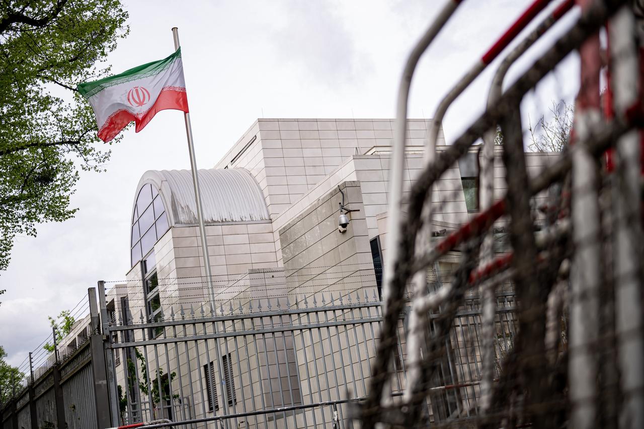 Absperrgitter stehen vor der iranischen Botschaft in Berlin. Über dem Gebäude weht eine iranische Flagge. 