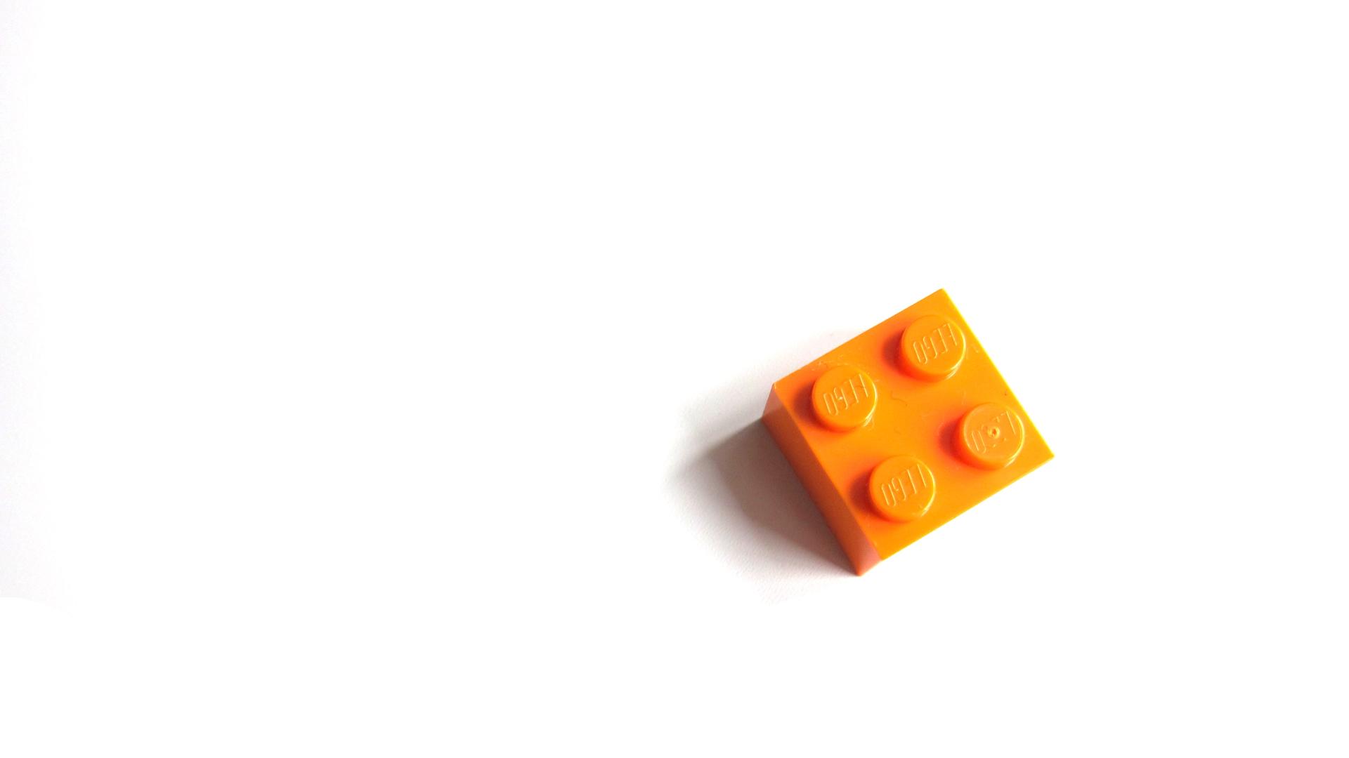 Ein orangener Legostein vor hellem Hintergrund. Ein orangener Legostein vor hellem Hintergrund.