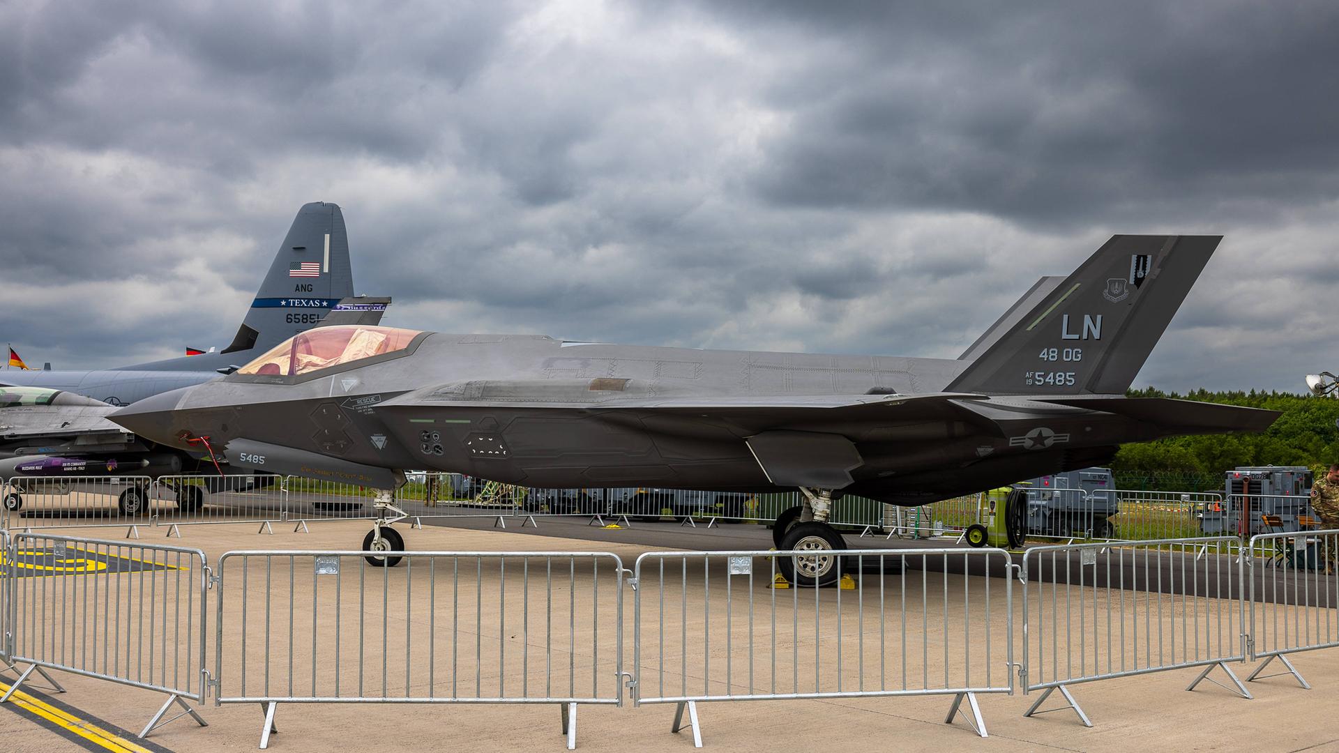Ein Lockheed Martin F-35A Lightning II der U.S. Air Force 48th Operations Group ist auf einem Freigelände als statisches Ausstellungsstück zu sehen. Im Hintergrund ist das Leitwerk eines weiteren Militärflugzeugs mit der Aufschrift Texas ANG erkennbar. Ein Lockheed Martin F-35A Lightning II der U.S. Air Force 48th Operations Group ist auf einem Freigelände als statisches Ausstellungsstück zu sehen. Im Hintergrund ist das Leitwerk eines weiteren Militärflugzeugs mit der Aufschrift Texas ANG erkennbar.