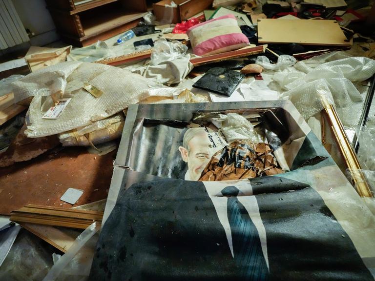 Ein kaputtes Porträt des verstorbenen syrischen Präsidenten Hafiz al-Assad liegt auf dem Boden, zusammen mit weiterem Hausrat, während Menschen in der Privatresidenz des gestürzten Präsidenten Baschar al-Assad in Damaskus nach Wertsachen suchen.