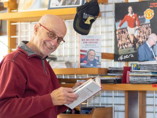 RadiolegendeGünther Koch steht im Büro in seinem Haus und lächelt in die Kamera.