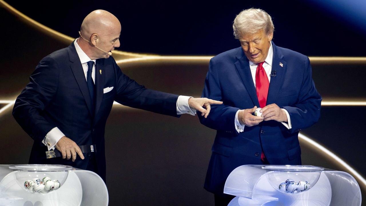 Gianni Infantino und Donald Trump stehen auf einer Bühne vor zwei Lostöpfen. Trump ist dabei, ein Los zu öffnen. Infantino zeigt auf ihn.