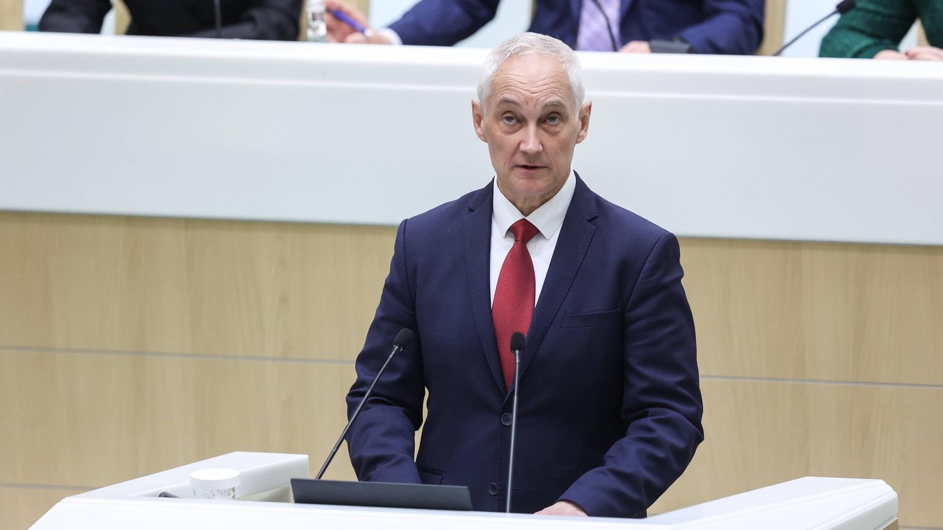 Der designierte russische Verteidigungsminister Beloussow spricht vor dem Parlament. Er steht an einem Pult und spricht in ein Mikrofon. Er trägt einen blauen Anzug, ein weißes Hemd und eine rote Krawatte. Der designierte russische Verteidigungsminister Beloussow spricht vor dem Parlament. Er steht an einem Pult und spricht in ein Mikrofon. Er trägt einen blauen Anzug, ein weißes Hemd und eine rote Krawatte.