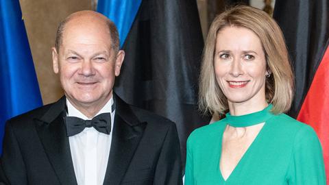 Bundeskanzler Olaf Scholz im Portrait mit Anzug und Fliege, neben ihm steht die Premierministerin Estlands, Kaja Kallas, in einem grünen Kleid.