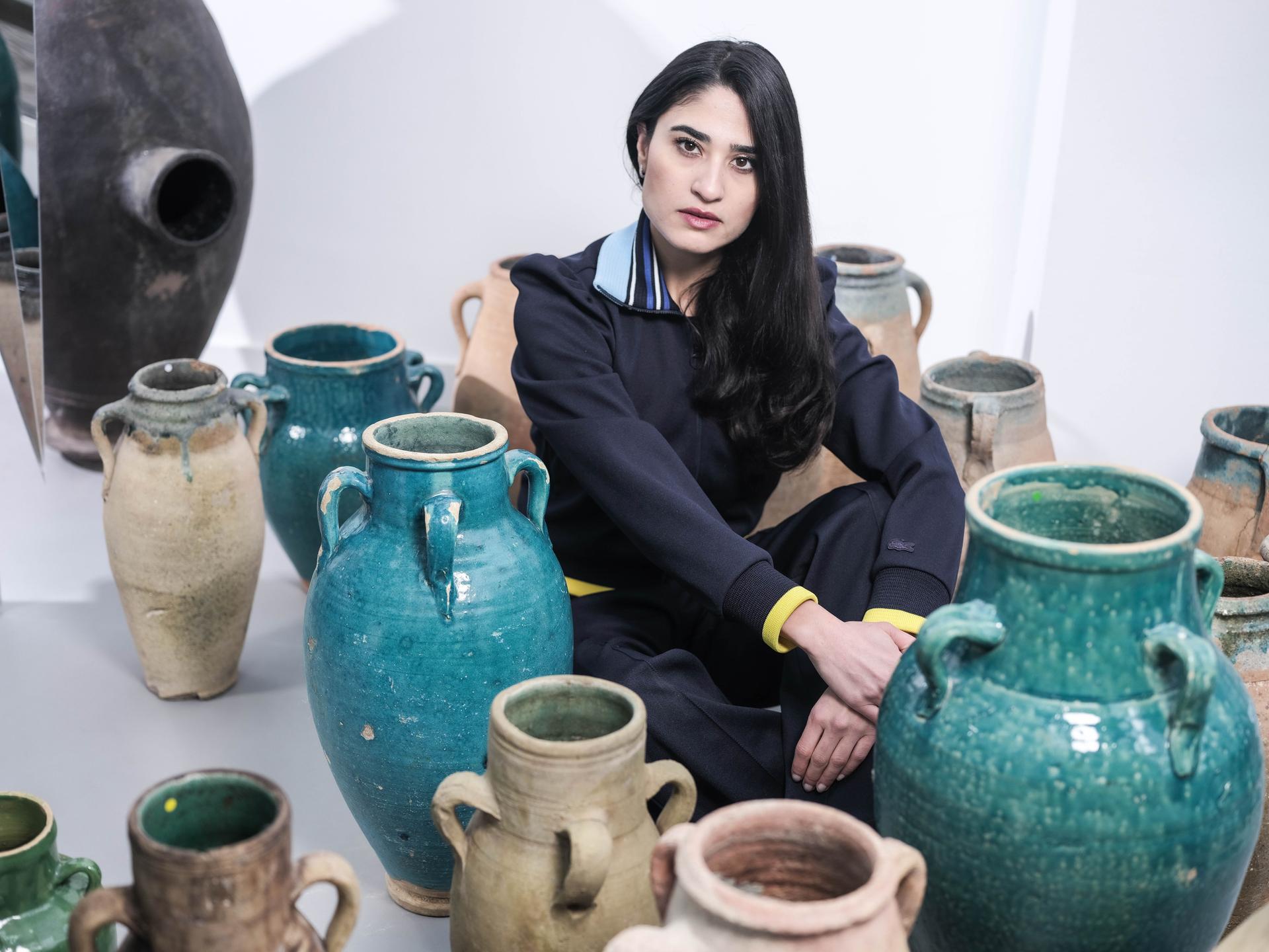 Anahita Sadighi sitzt zwischen großen Keramikvasen