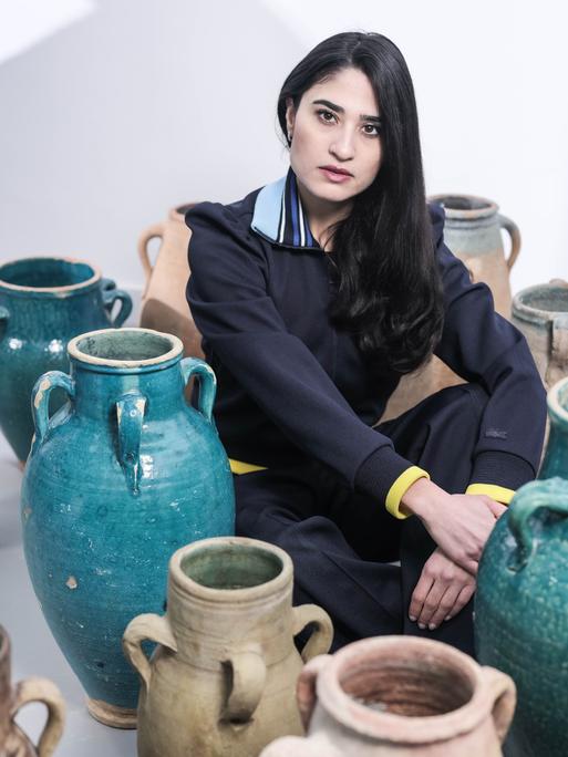 Anahita Sadighi sitzt zwischen großen Keramikvasen