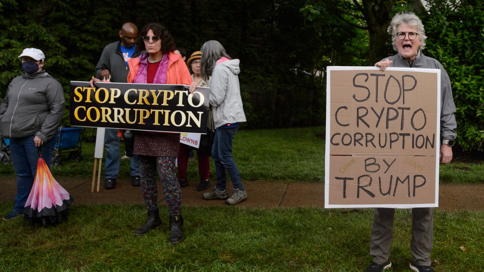 Das Foto zeigt Demonstranten bei einem Golfclub von Präsident Trump. Auf Schildern steht "Stopp die Krypto-Korruption". Das Foto zeigt Demonstranten bei einem Golfclub von Präsident Trump. Auf Schildern steht "Stopp die Krypto-Korruption".